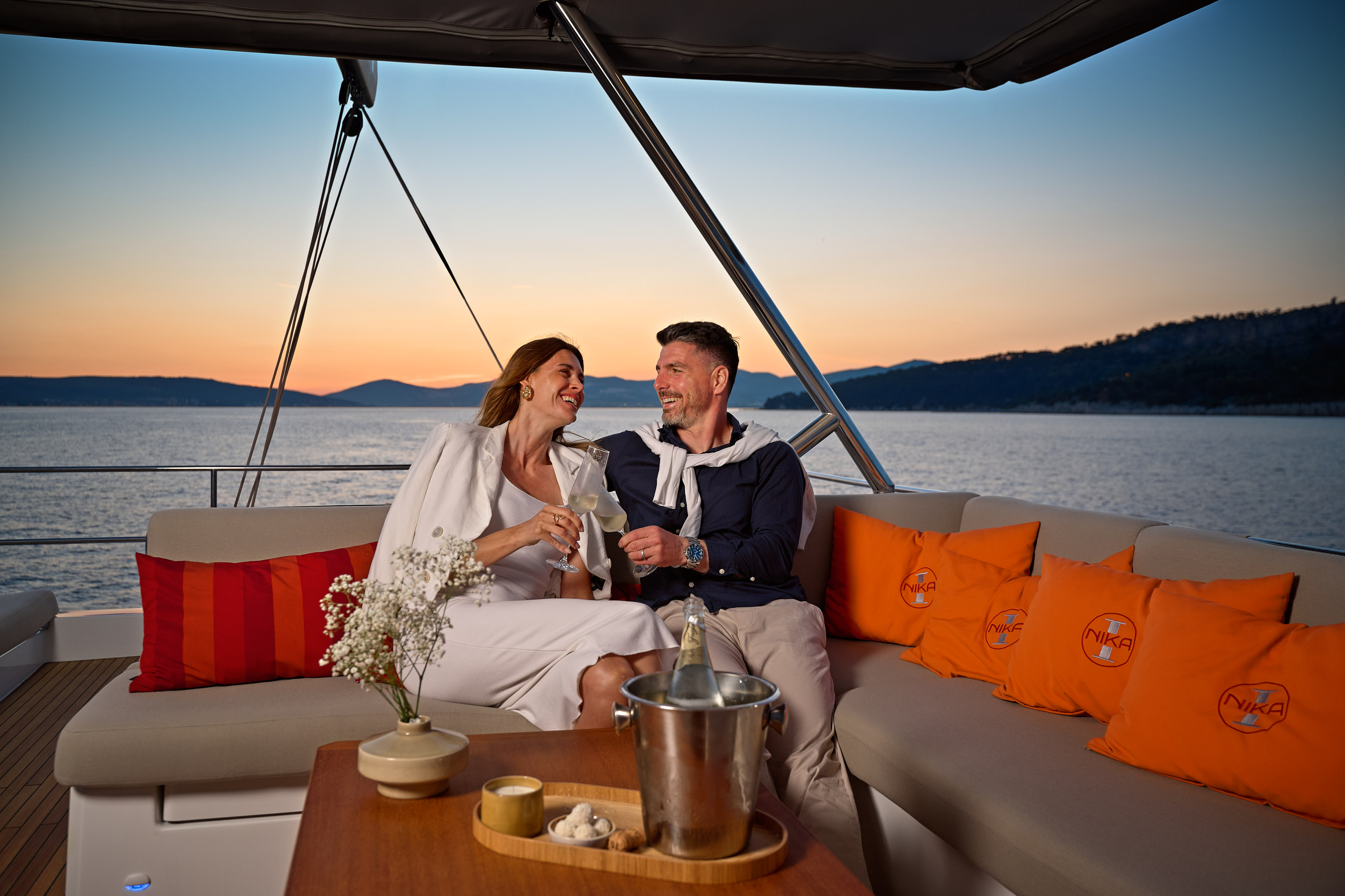 Guests toasting champagne at sunset aboard NIKA I